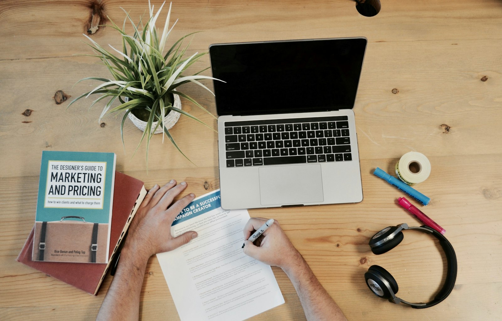A marketing workspace with a planning book, laptop and notes for campaign strategy