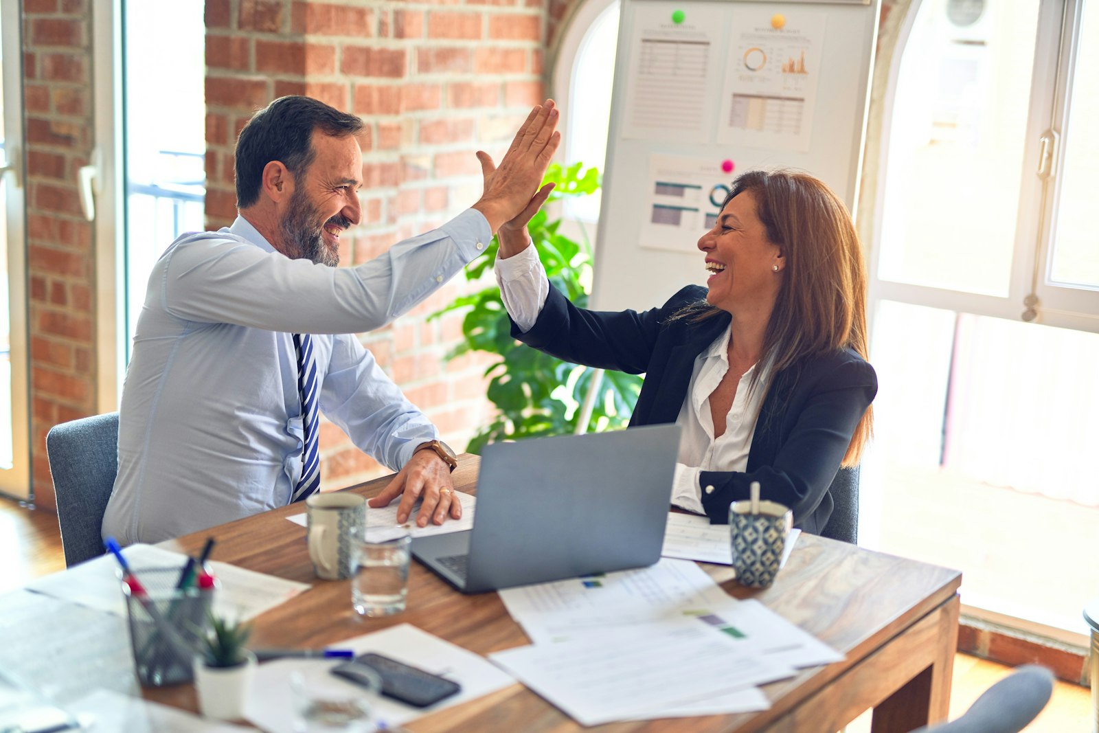 Two colleagues celebrating a win at a workspace desk