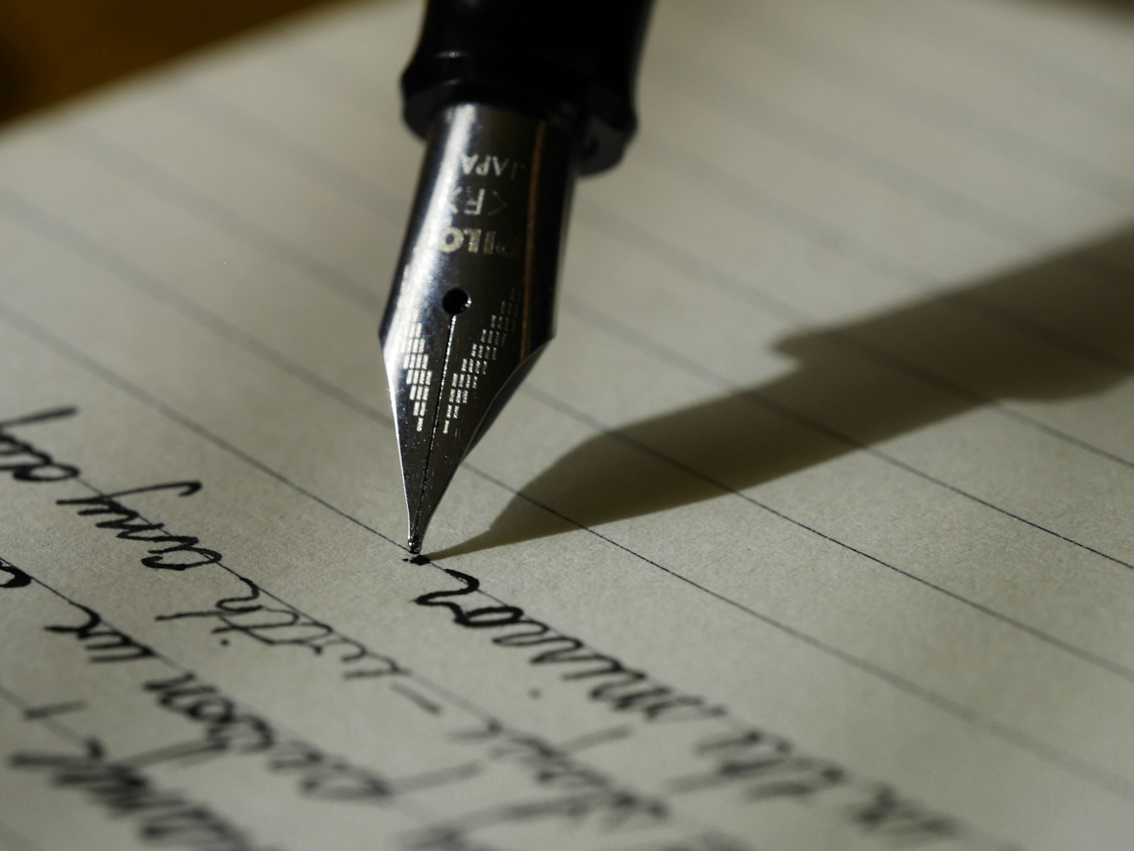 A fountain pen writing in cursive on lined paper
