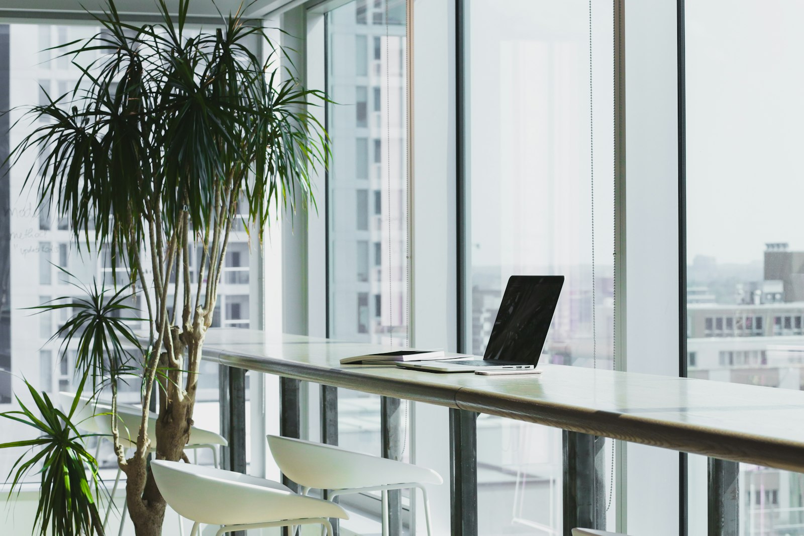 A laptop on a counter beside a window overlooking a city skyline